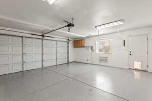 Garage with a wall mounted AC and a garage door opener