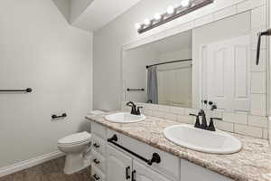 Bathroom with double vanity, dark wood-style flooring, and curtained shower