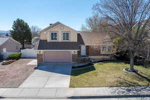 Traditional-style house featuring a shingled roof, an attached garage, brick siding, concrete driveway, and stucco siding