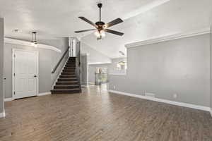 Unfurnished living room featuring dark wood-style floors and a ceiling fan