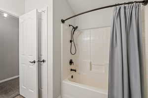 Bathroom featuring shower / tub combo with curtain and baseboards