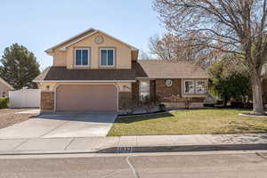 Traditional home with a shingled roof, a front yard, concrete driveway, an attached garage, and stucco siding