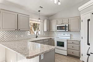 Kitchen with a peninsula, white appliances, gray cabinets, and light countertops
