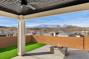 Fenced backyard with ceiling fan, an outdoor fire pit, a mountain view, a patio, and a residential view