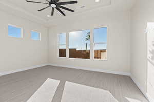 Empty room with light carpet, a ceiling fan, a raised ceiling, and recessed lighting
