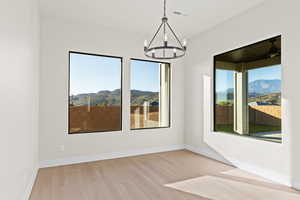 Spare room with light wood finished floors, a mountain view, and suspended lighting
