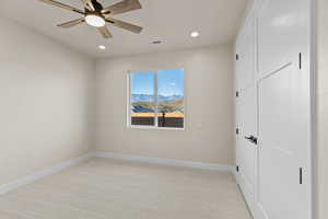 Unfurnished bedroom with light carpet, ceiling fan, recessed lighting, and a mountain view