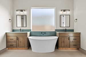 Bathroom featuring two vanities, light tile patterned floors, a soaking tub, and tile walls