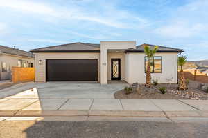View of front of house with an attached garage, driveway, a tile roof, and stucco siding
