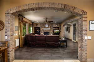 Living room featuring arched walkways, a fireplace, wood finished floors, a ceiling fan, and recessed lighting