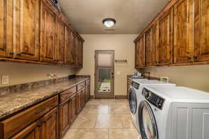 Laundry area with cabinet space, washing machine and clothes dryer, and light tile patterned floors