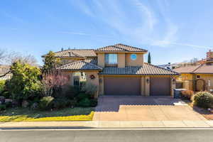 Mediterranean / spanish house with an attached garage, concrete driveway, stucco siding, and a tiled roof