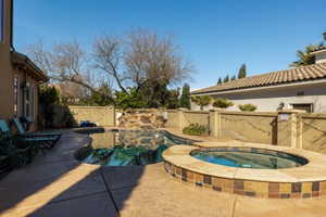 Integrated pool / spa with a fenced backyard and a patio