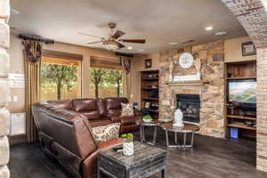 Living room with ceiling fan, dark wood-style floors, a fireplace, and recessed lighting