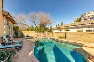 View of swimming pool with patio surround and a fenced backyard