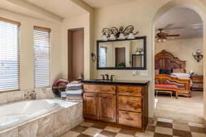 Ensuite bathroom featuring vanity, light floors, a bath, a ceiling fan, and healthy amount of natural light
