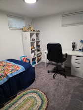 Bedroom with dark carpet and an office area