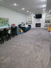 Carpeted living room with built in features, recessed lighting, a textured ceiling, and a fireplace