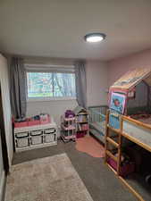 Bedroom featuring dark carpet and a crib