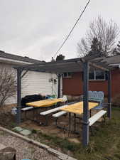 Rear view of house featuring a patio area, a pergola, and brick siding