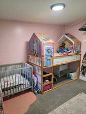 Carpeted bedroom featuring a nursery area