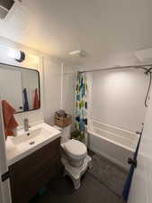 Bathroom featuring vanity, shower / tub combo, a textured ceiling, and dark tile patterned floors
