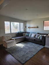 Living area with dark wood-type flooring, healthy amount of natural light, and recessed lighting