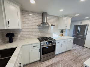 Kitchen with stainless steel appliances, light stone counters, white cabinets, recessed lighting, and decorative backsplash