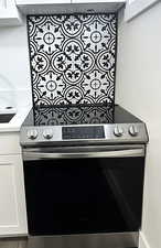 Kitchen view of stainless steel electric stove, white cabinetry, and light stone countertops