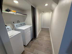Laundry area with light wood-type flooring, recessed lighting, and washing machine and dryer