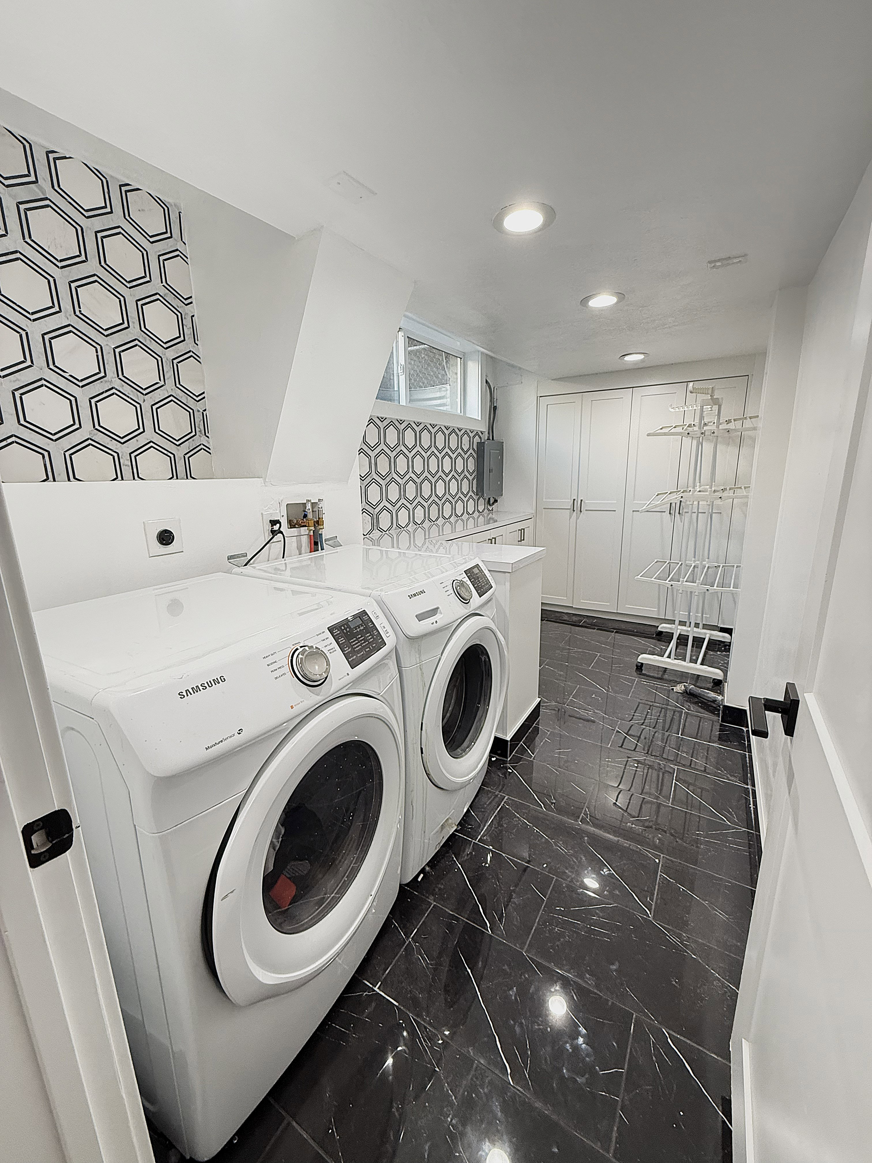 Laundry room featuring washer and clothes dryer, electric panel, and dark marble finish flooring