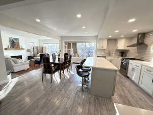 Kitchen featuring gas stove, a fireplace, a kitchen breakfast bar, a center island, and plenty of natural light