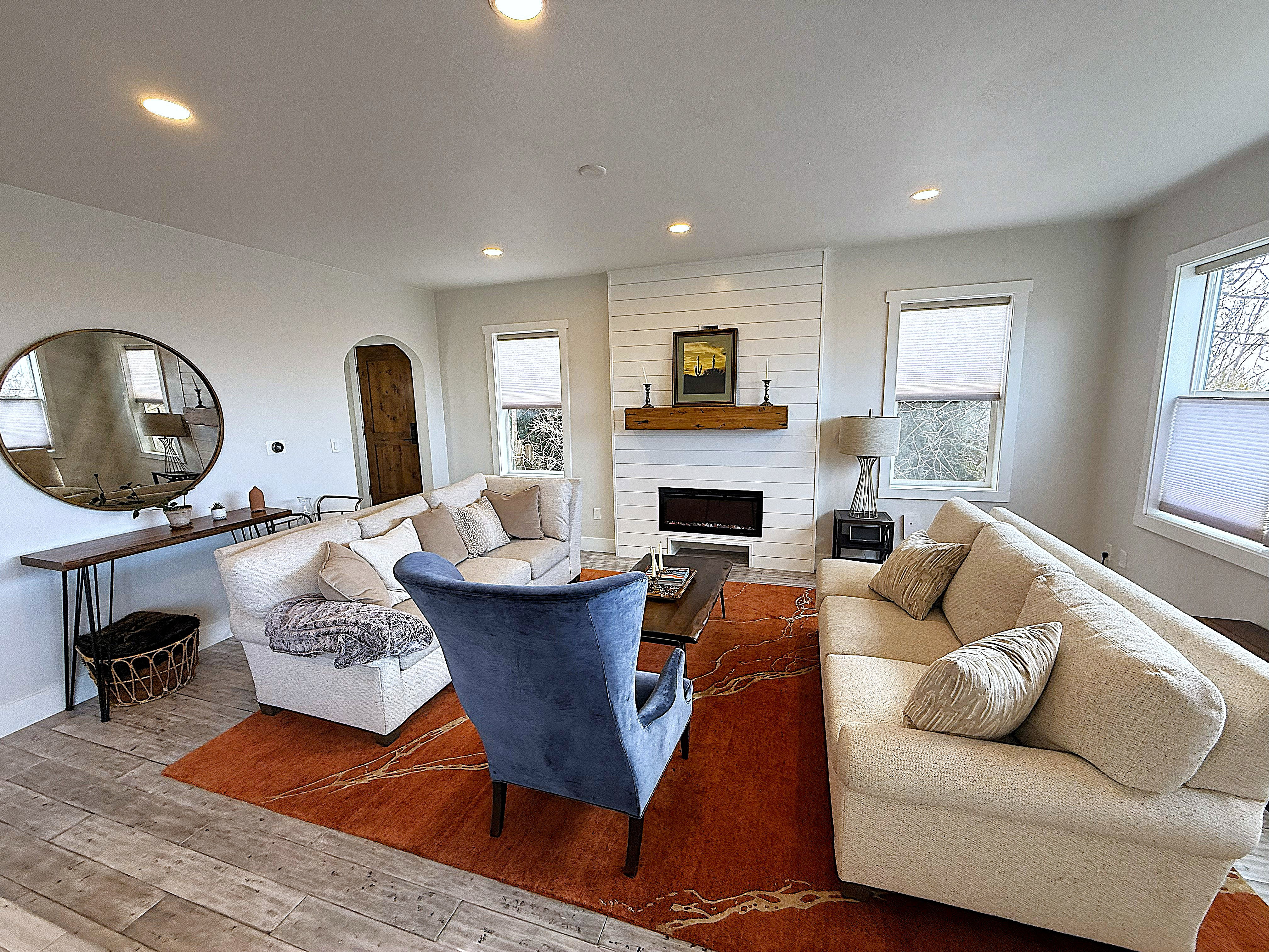Living room featuring arched walkways, recessed lighting, wood-type flooring, and a large fireplace