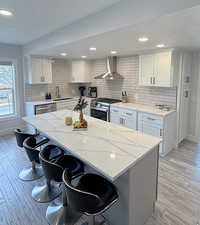 Kitchen featuring a breakfast bar area, white cabinetry, a kitchen island, stainless steel appliances, and light wood-type flooring