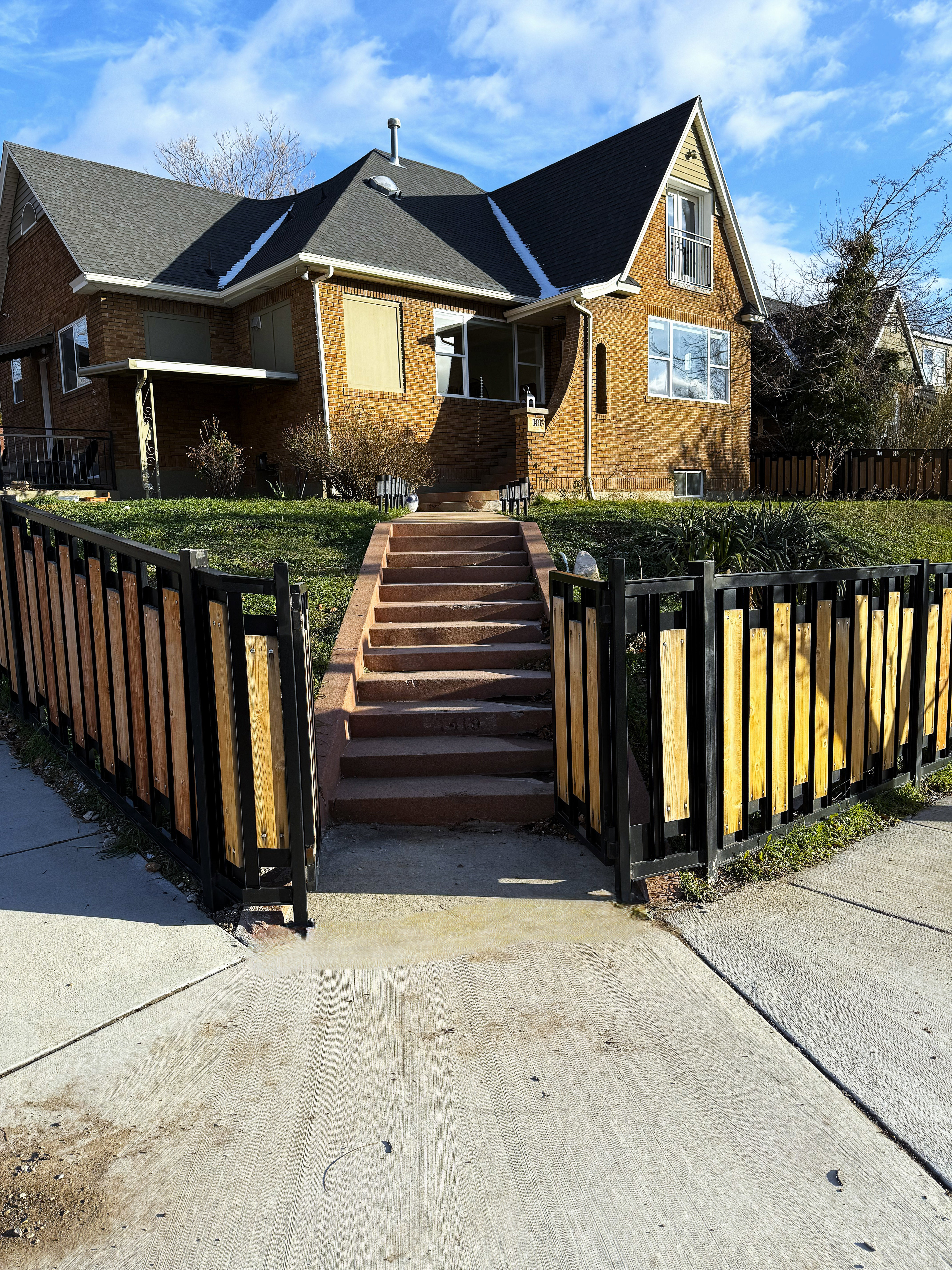 View of front facade featuring brick siding, a fenced front yard, a gate, and roof with shingles