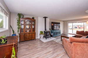 Living area featuring a wood stove, light wood-style floors, and a textured ceiling