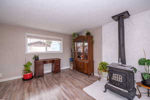 Living area with a wood stove, light wood-style flooring, and a textured ceiling