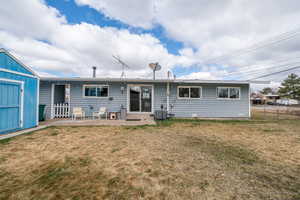 Rear view of property with a shed and a patio area