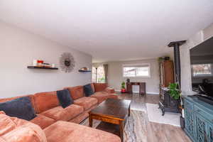 Living room featuring a wood stove, light wood-style flooring, and a textured ceiling