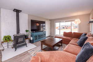 Living room with a wood stove, wood finished floors, and a textured ceiling