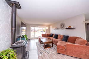 Living area with a wood stove, light wood-style flooring, and a textured ceiling