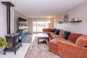 Living room featuring a wood stove, light wood finished floors, and a textured ceiling