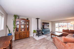 Living area with light wood finished floors, a wood stove, and a textured ceiling