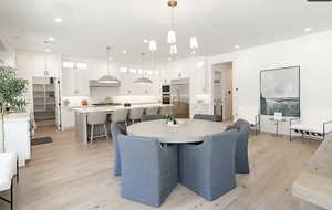 Dining area with light wood finished floors and recessed lighting