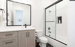 Bathroom featuring vanity, enclosed tub / shower combo, and dark tile patterned flooring