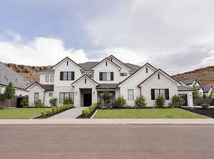 Modern inspired farmhouse with stone siding, board and batten siding, and a front lawn