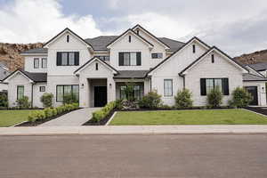 Modern inspired farmhouse featuring stone siding, board and batten siding, and a front yard