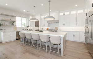 Kitchen with a kitchen bar, a center island, tasteful backsplash, hanging light fixtures, and white cabinets