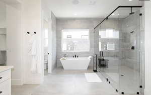 Bathroom with a soaking tub, a stall shower, light tile patterned floors, vanity, and tile walls