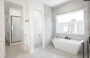 Bathroom with a freestanding tub, tile walls, light tile patterned flooring, and vanity